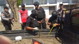 Petugas Jihandak Brimob Polda Jatim meminta warga menjauh dari TKP saat proses evakuasi mortir. (istimewa)