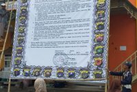 Warga membaca baliho raksasa yang dipasang petugas Polres Sumenep di Pasar Anom, Senin, 23/03/2020. (*/istimewa) 