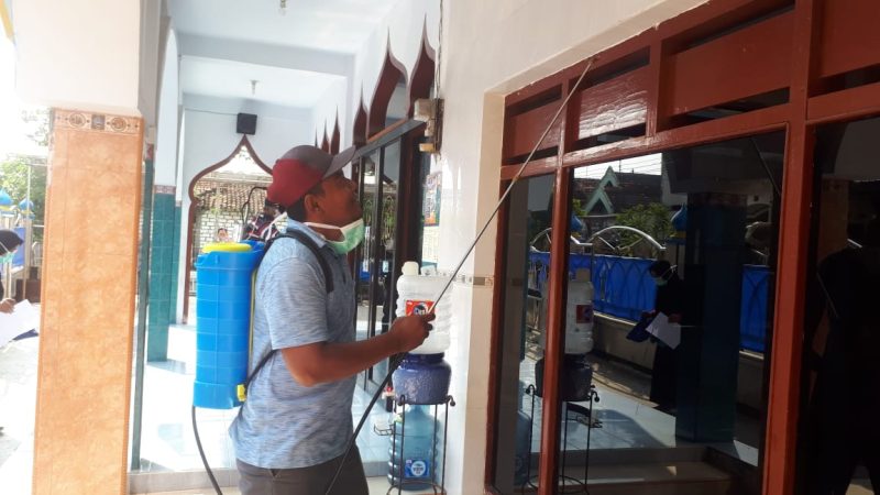 Petugas menyemprotkan desinfektan di areal masjid di Desa Sidogembul, Jumat, 27/03/2020. (Makhrus/SJ Foto) 