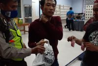 Seorang pria (berkaos merah) ditangkap saat akan memasok pil diduga narkoba ke Lapas Porong, Senin, 30/03/2020. (Yudha/SJ Foto) 