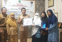 TERSENYUM: Kepala Dinas Sosial Sumenep, Mustangin, saat memberikan sertifikar kepada Direktur Paud El-Fath, Nurul Hayati (Sandi GT - Seputar Jatim)