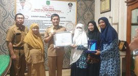 TERSENYUM: Kepala Dinas Sosial Sumenep, Mustangin, saat memberikan sertifikar kepada Direktur Paud El-Fath, Nurul Hayati (Sandi GT - Seputar Jatim)