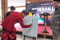 TAMPIL: Sekretaris Daerah (Sekda) Kabupaten Sumenep, Edy Rasyadi, saat melukis sebagai tanda membuka pameran lukisan (SandiGT - Seputar Jatim)