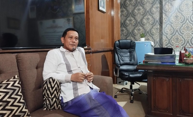 BERSARUNG : Kepala Dinsos Sumenep, Mustangin, saat ditemui wartawan seputarjatim.com di ruangan kerjanya (SandiGT - Seputar Jatim)