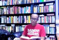 MEMBACA: Budayawan Sumenep, Ibnu Hajar, saat berada di antara tumpukan buku di perpustakaan pribadinya di rumahnya (Doc. Seputar Jatim)