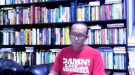 MEMBACA: Budayawan Sumenep, Ibnu Hajar, saat berada di antara tumpukan buku di perpustakaan pribadinya di rumahnya (Doc. Seputar Jatim)