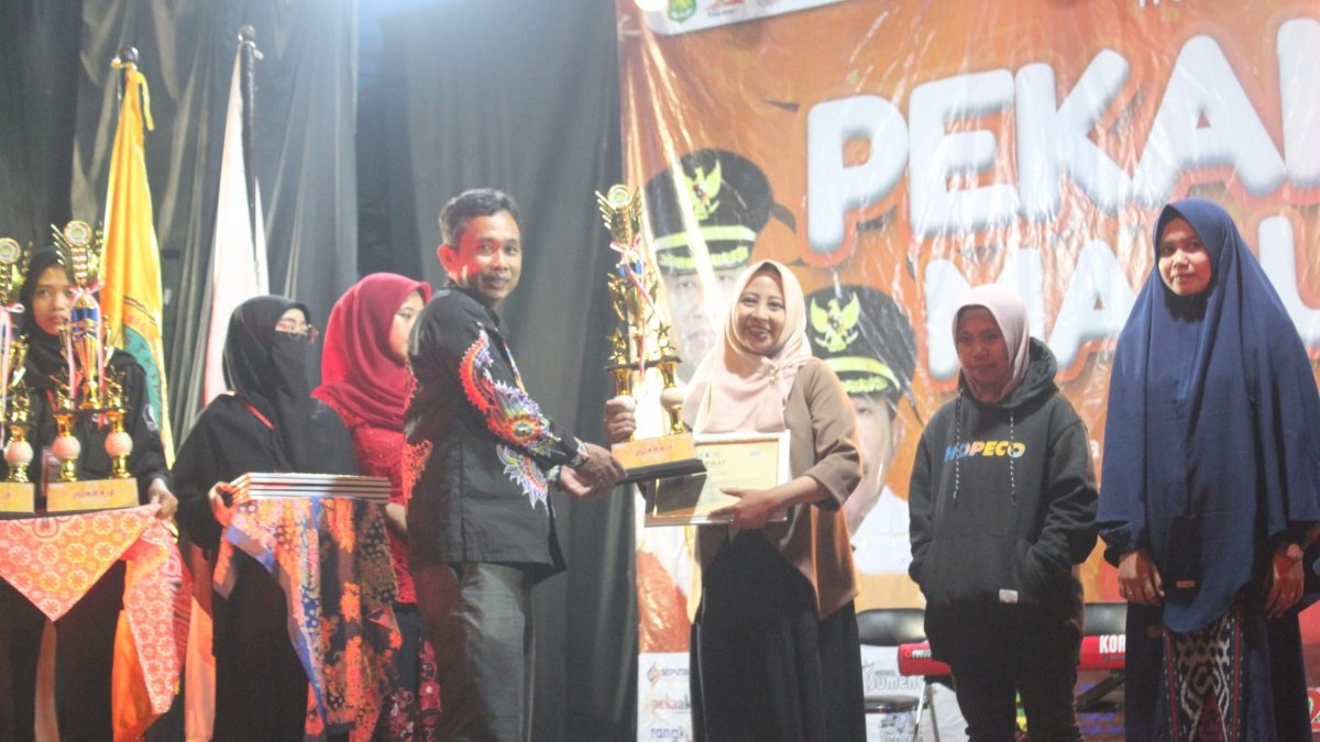 BAHAGIA: Ketua STKIP PGRI Sumenep, Asmoni, saat menyerahkan trophy kepada pemenang lomba baca puisi pada penutupan acara PSM ke-9 (SandiGT - Seputar Jatim)