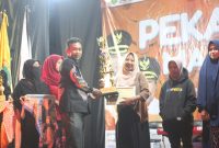 BAHAGIA: Ketua STKIP PGRI Sumenep, Asmoni, saat menyerahkan trophy kepada pemenang lomba baca puisi pada penutupan acara PSM ke-9 (SandiGT - Seputar Jatim)