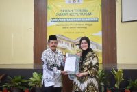 TERSENYUM: Ketua LLDIKTI Wilayah VII Jawa Timur,  Dyah Sawitri (kanan) saat menyerahkan Salinan Keputusan Menteri Pendidikan Tinggi kepada Ketua PPLP-PT PGRI Sumenep, Sunarjo (kiri) (SandiGT - Seputar Jatim)