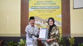 TERSENYUM: Ketua LLDIKTI Wilayah VII Jawa Timur,  Dyah Sawitri (kanan) saat menyerahkan Salinan Keputusan Menteri Pendidikan Tinggi kepada Ketua PPLP-PT PGRI Sumenep, Sunarjo (kiri) (SandiGT - Seputar Jatim)