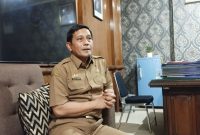 SANTAI: Kepala Dinsos P3A Sumenep, Mustangin, saat menyampaikan tentang DBHCHT di ruangannya (SandiGT - Seputar Jatim)