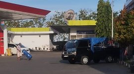 SANTAI: Terlihat sesorang mendorong jerigen berisi BBM Solar yang akan diangkut ke mobil Pick Up hitam di SPBU Patean Sumenep (SandGT- Seputar Jatim)