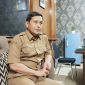 SANTAI: Kepala Dinsos P3A Sumenep, Mustangin, saat diwawancarai tentang program sekolah gratis di ruangannya (SandiGT - Seputar Jatim)