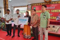 BERJEJER: Kepala Disnaker Sumenep, Heru Susanto, (kiri) bersama Bupati Sumenep, Achmad Fauzi Wongsojudo (tengah) saat menyerahkan BPJS Ketenagakerjaan secara simbolis kepada salahsatu pekerja (SandiGT - Seputar Jatim) 