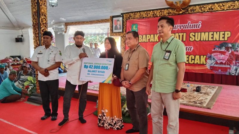 BERJEJER: Kepala Disnaker Sumenep, Heru Susanto, (kiri) bersama Bupati Sumenep, Achmad Fauzi Wongsojudo (tengah) saat menyerahkan BPJS Ketenagakerjaan secara simbolis kepada salahsatu pekerja (SandiGT - Seputar Jatim) 