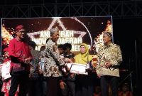 SERAH TERIMA: Kepala Bidang Pelayanan Pendaftaran Penduduk Disdukcapil Sumenep, Wahasah, saat menerima penghargaan inovasi daerah 2025, yang diberikan oleh Plt Sekda R. Achmad Syahwan Effendy (SandiGT - Seputar Jatim) 