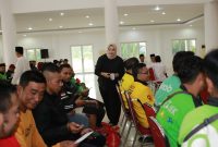 BAHAGIA: Seorang perempuan membagikan bantuan kepada para pengemudi ojek online saat kegiatan sosial Ramadan di Islamic Center Sumenep (Doc. Seputar Jatim)