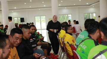 BAHAGIA: Seorang perempuan membagikan bantuan kepada para pengemudi ojek online saat kegiatan sosial Ramadan di Islamic Center Sumenep (Doc. Seputar Jatim)
