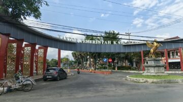 CERAH: Pintu masuk Kantor Pemerintah Kabupaten Sumenep tampak dari depan, dengan sejumlah kendaraan, termasuk becak dan mobil, melintasSeputar Jatim)