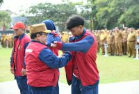 BERSEMANGAT: Wakil Bupati Sumenep, KH. Imam Hasyim, memakaikan jaket kontingen kepada atlet pelajar Kabupaten Sumenep saat pelepasan menuju POPDA Jatim XV 2026 (Dok. Seputar Jatim)