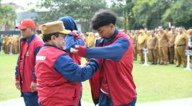 BERSEMANGAT: Wakil Bupati Sumenep, KH. Imam Hasyim, memakaikan jaket kontingen kepada atlet pelajar Kabupaten Sumenep saat pelepasan menuju POPDA Jatim XV 2026 (Dok. Seputar Jatim)